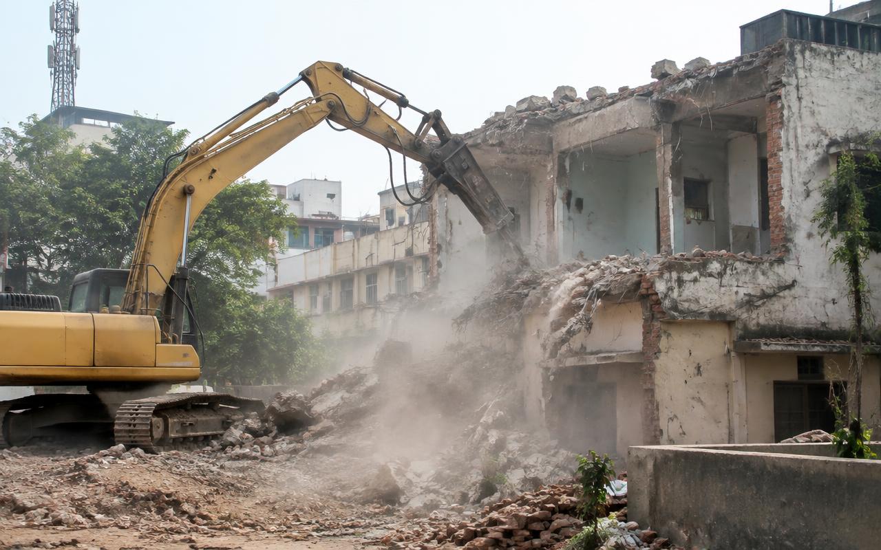 Controlled demolition of an old building with an excavator breaker before redevelopment
